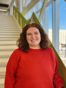 A photo of a woman standing on stairs smiling.